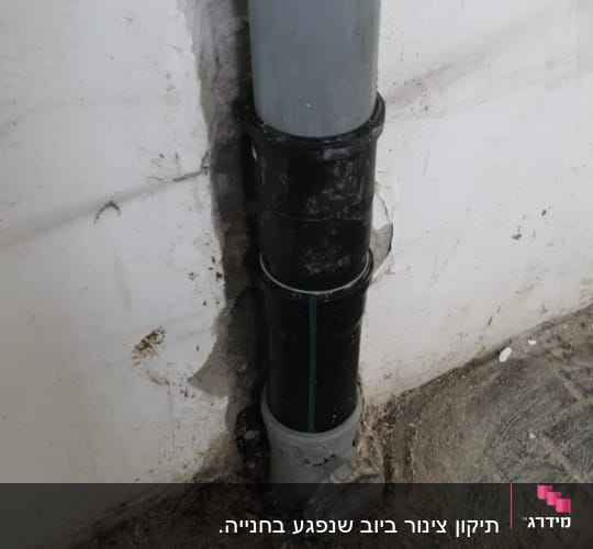 צינור ביוב מותקן בקיר עם טיח מתקלף